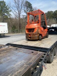 Forklift-class equipment secured on open deck for shipping
