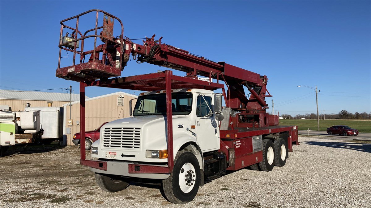 Red digger derrick utility truck staged for transport
