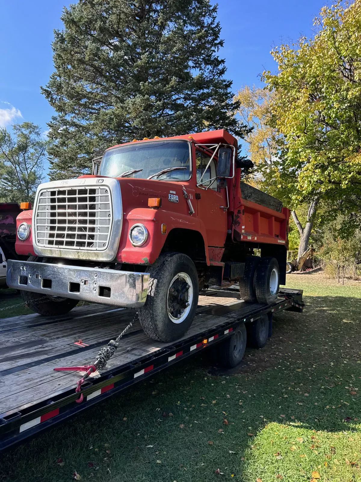 Red Ford dump truck secured with chains on flatbed trailer